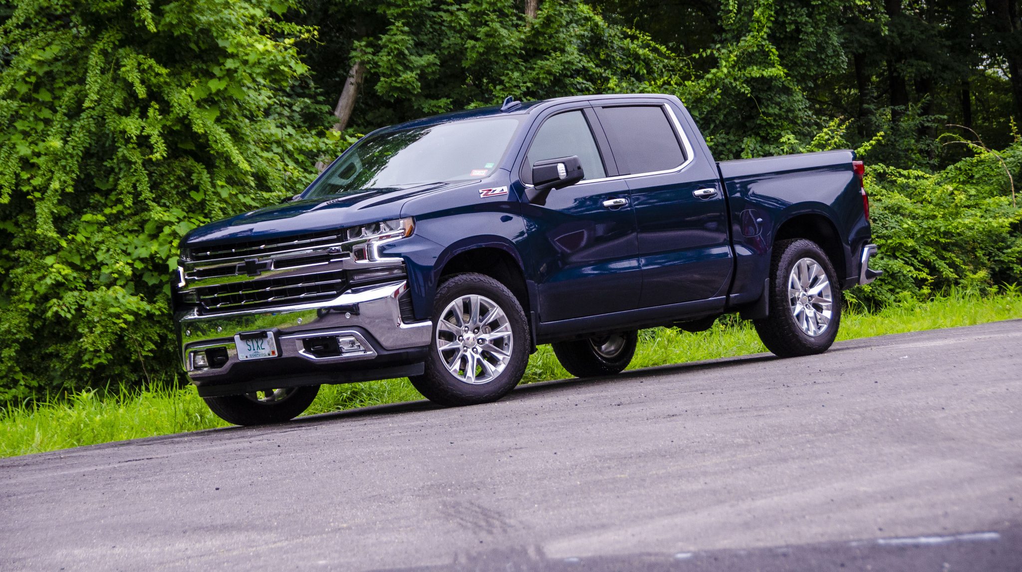 Chevy Silverado in Northsky Blue Metallic With a green forest behind it