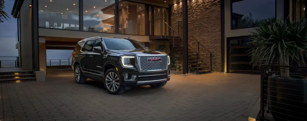 2023 GMC Yukon Denali passenger front 3/4 view in Onyx Black parked in front of house.