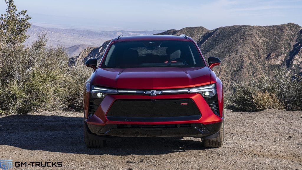 A red Chevy Blazer EV parked next to an overlook with mountains in the background