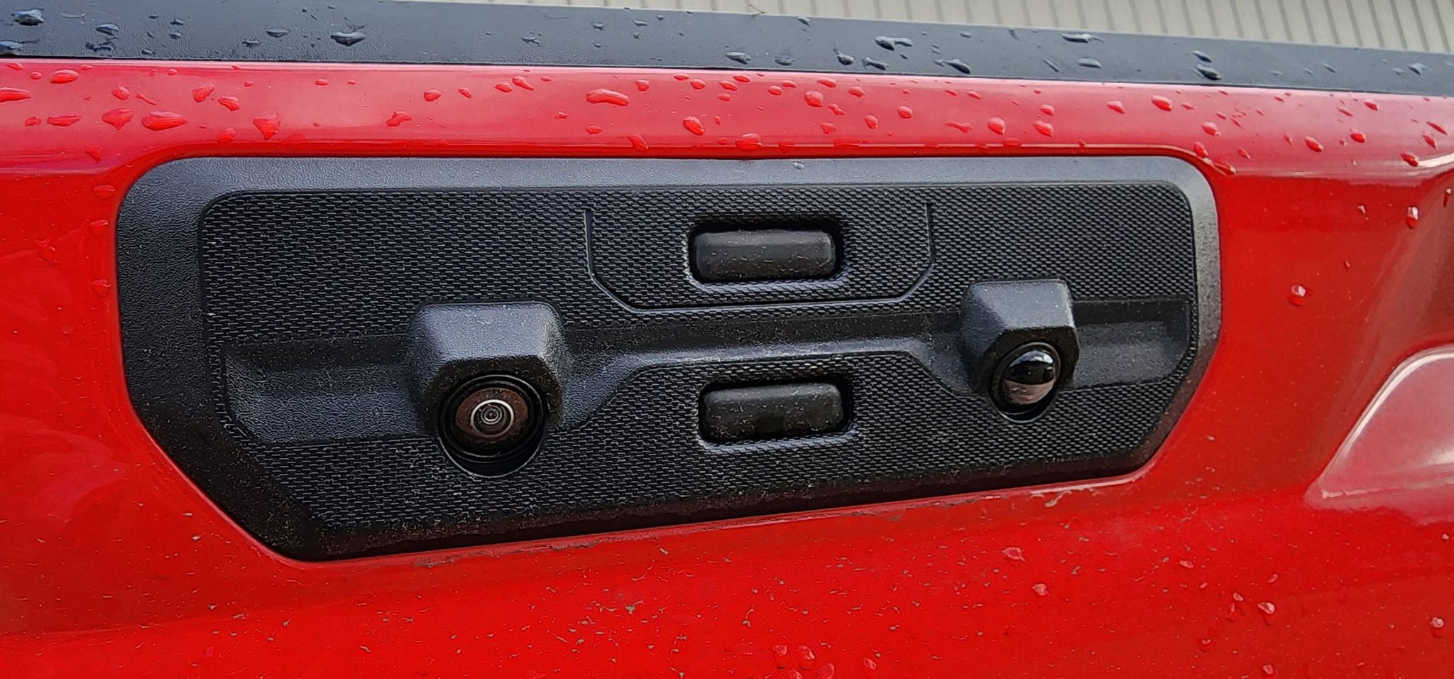 Close-up of a Chevrolet Silverado or GMC Sierra tailgate touchpad with integrated cameras, showing potential areas affected by water intrusion.